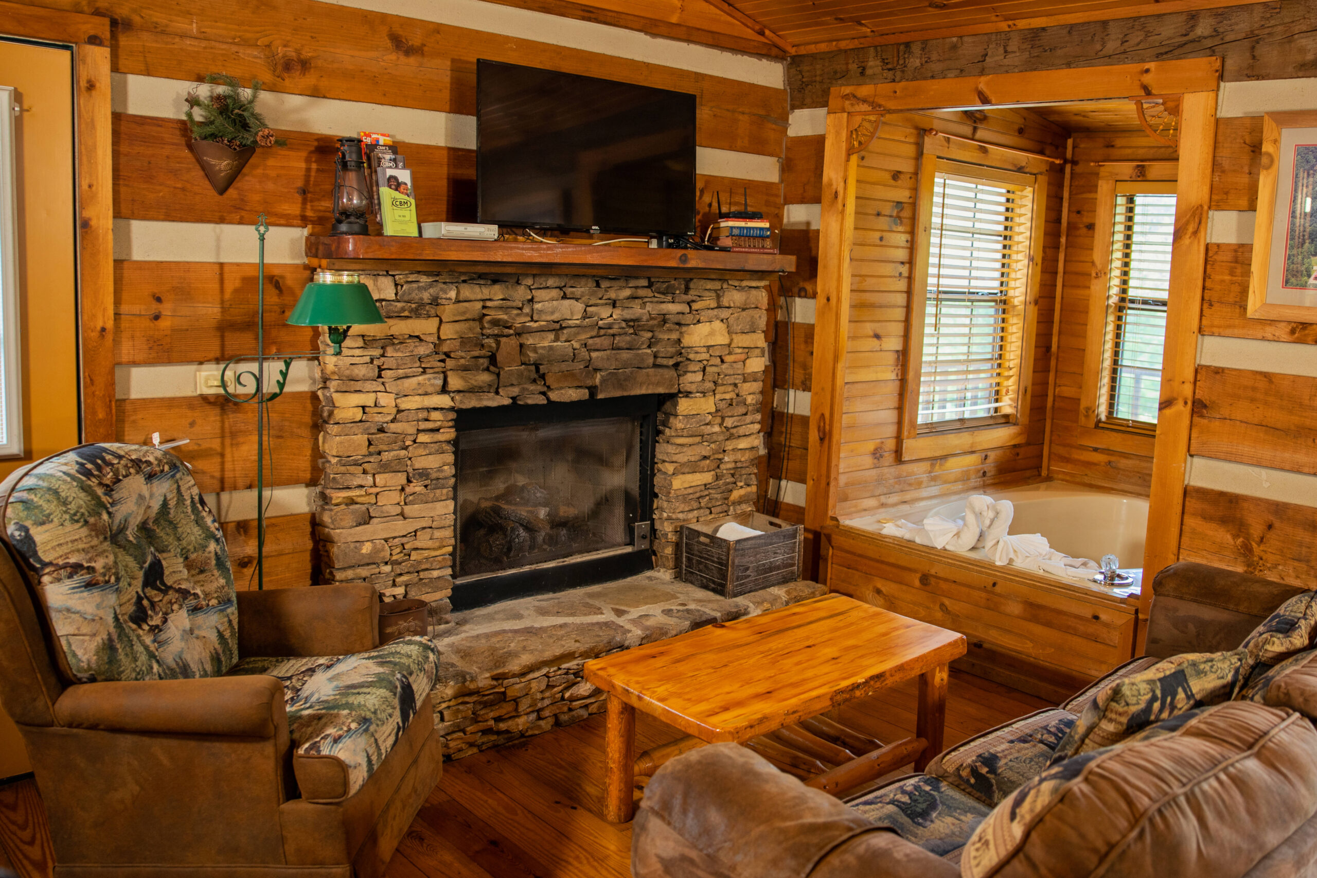 living room area with stone fireplace, hot tub and sofa